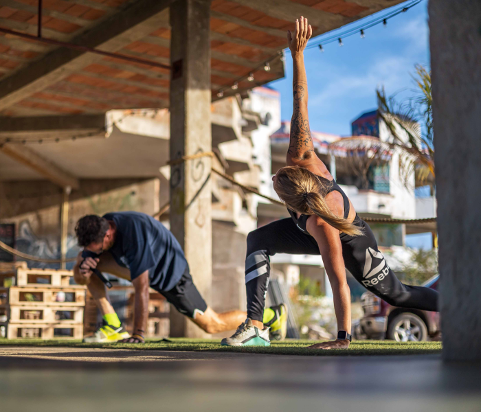 Image of a woman and a men stretching and on the background you can see why crossfit palms has the most unique crossfit location of bonaire.