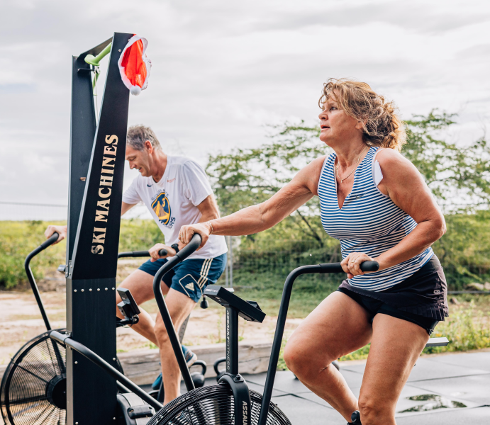 Image of a man and a women working out on an assult bike outdoor on bonaire.
